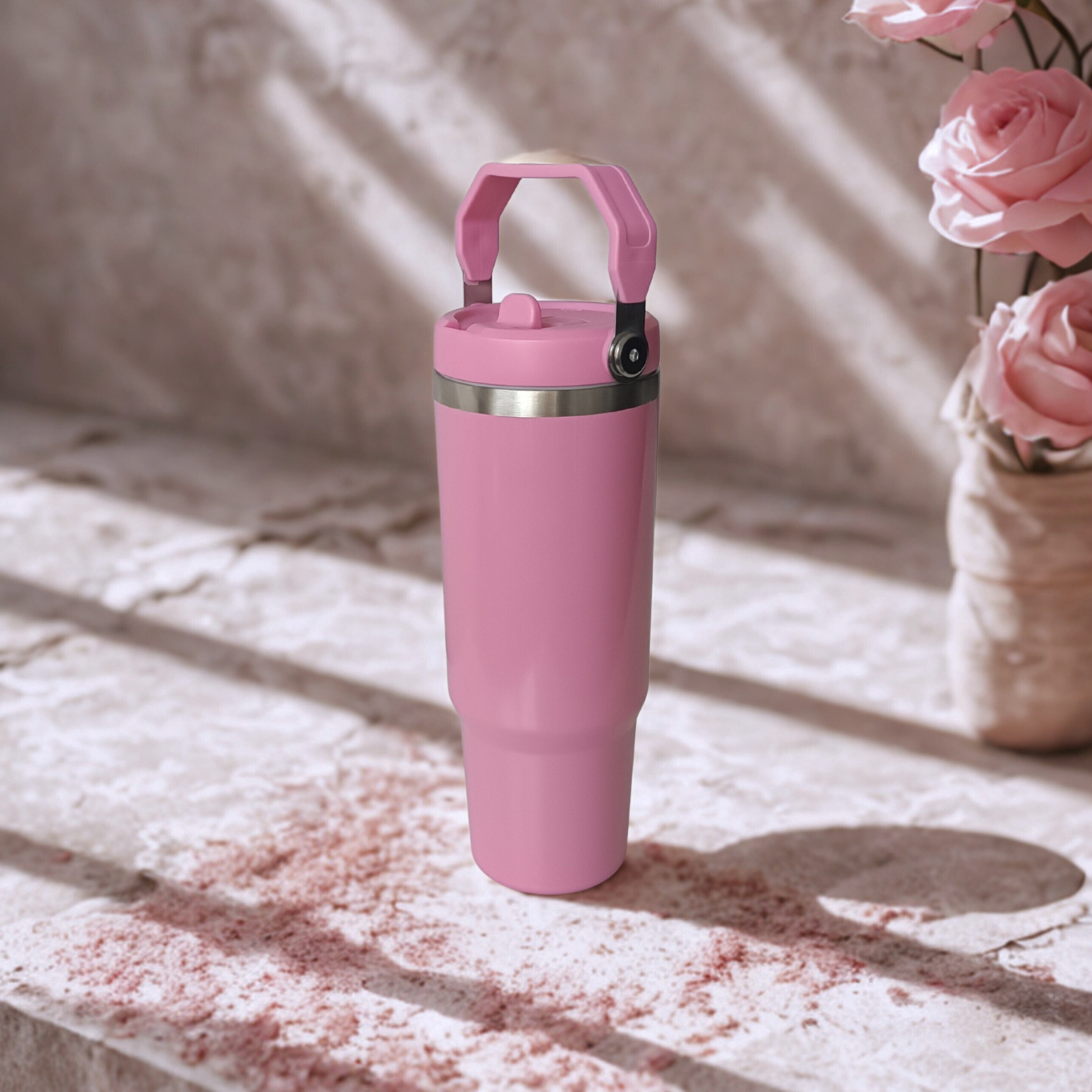 Front view of the Rose Dust tumbler with upright handle beside roses in warm filtered light