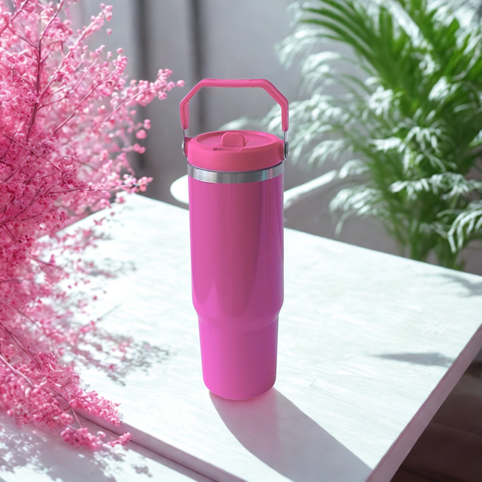Front view of the Wildberry Pink tumbler with upright handle, placed on a sunlit white table with vibrant florals